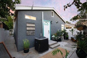 Stylish residence with a modern exterior, featuring a small outdoor area with potted plants and a heater.