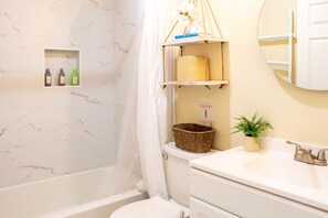 Bathroom features a toilet, sink, and shelf with storage.