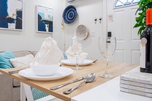 A dining area with a table set for a meal, featuring a plate, glass, and wine glass, along with cutlery.