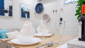 A dining table set with white plates, bowls, and wine glasses, with a bottle of wine on the right.