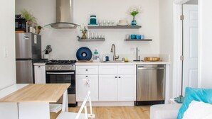 A modern kitchen with white cabinets, stainless steel appliances, and a wooden dining table.