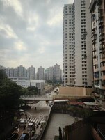 Un edificio alto con varios pisos y balcones, rodeado de otros edificios.