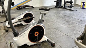 Un gimnàs amb equip d'exercici, incloent una bicicleta estática i màquines de peses.