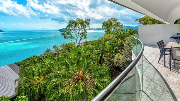 A balcony with a glass railing overlooking a turquoise sea and lush greenery. - Waves 2 - Ocean views with buggy (Whitsundays)