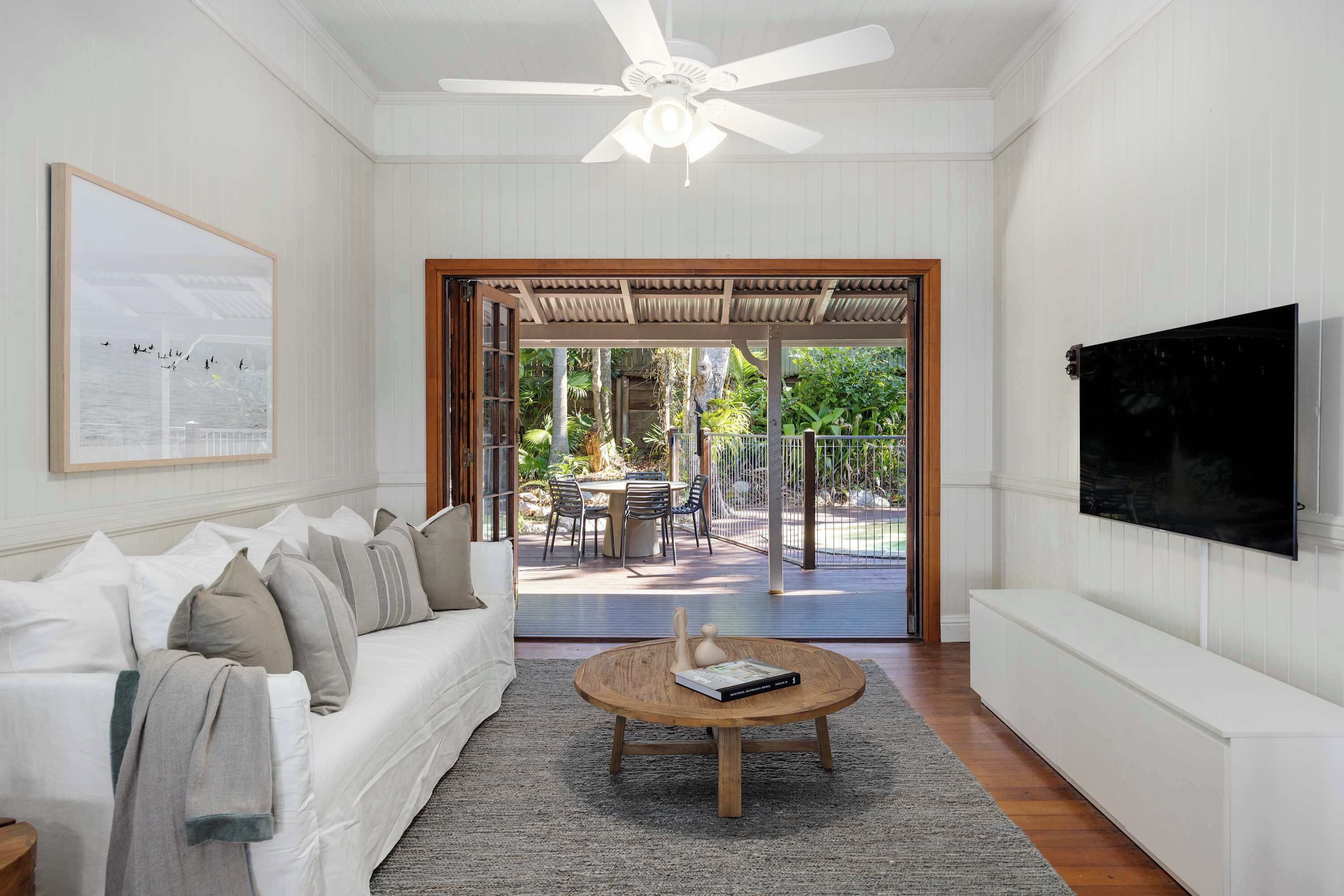 A living room with a white sofa, a coffee table, a TV, and a view of an outdoor patio.