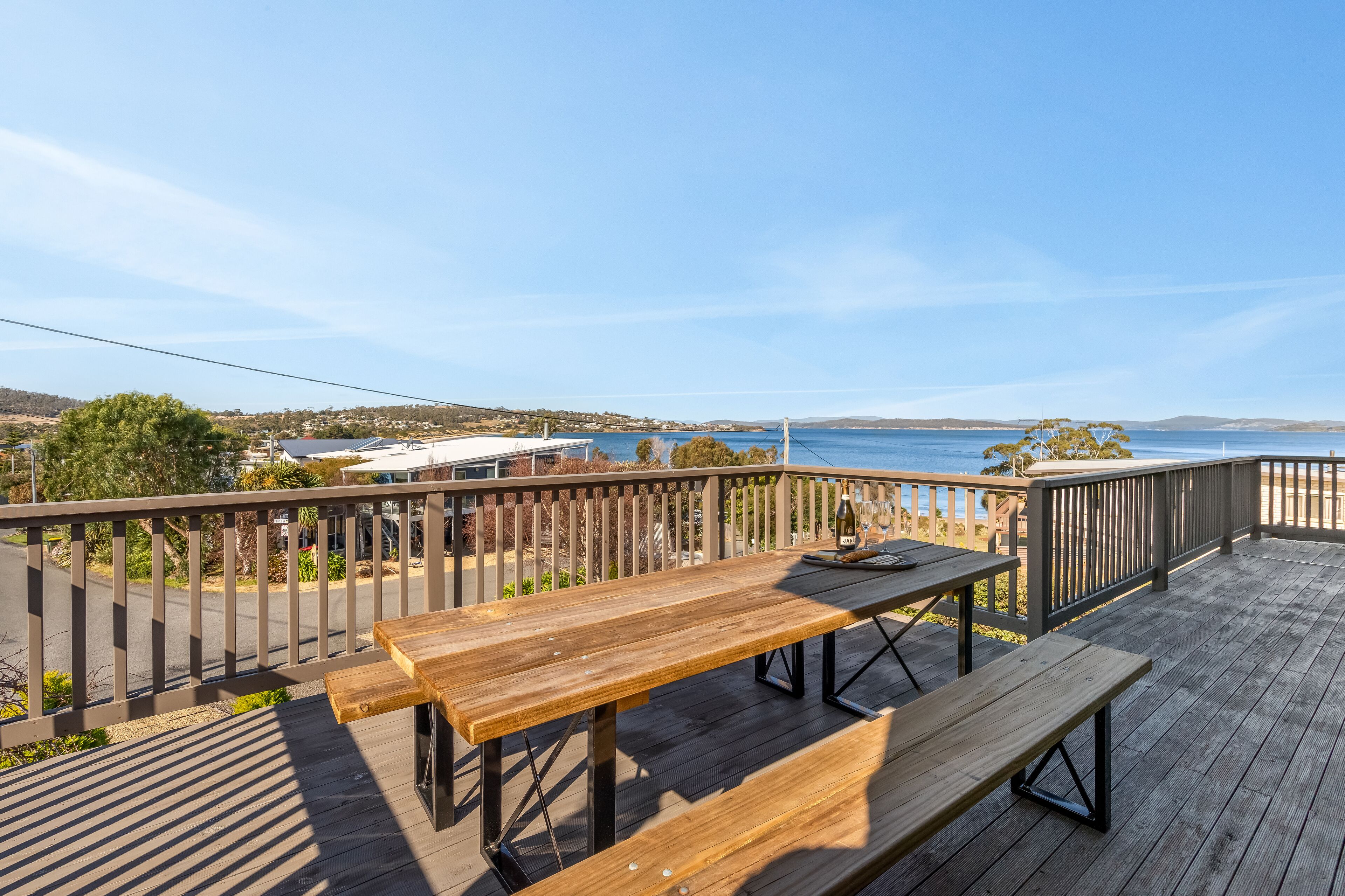 Eine Holzterrasse mit Picknicktischen mit Blick auf eine Küstenlandschaft.