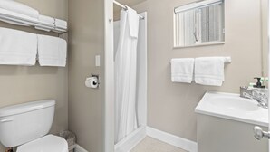A bathroom with a toilet, a shower, a sink, and towels on a rack. - Cozy 2 Bedroom Suite at Lazy Duck Inn, just 1 minute from Yellowstone! Lazy Duck 16 (West Yellowstone)
