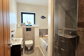 A modern bathroom with a toilet, sink, and shower.