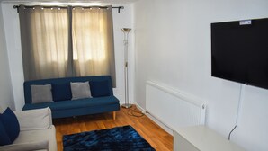 Una sala de estar con un sofá azul, un armario blanco, un tapete azul y una lámpara de pie.