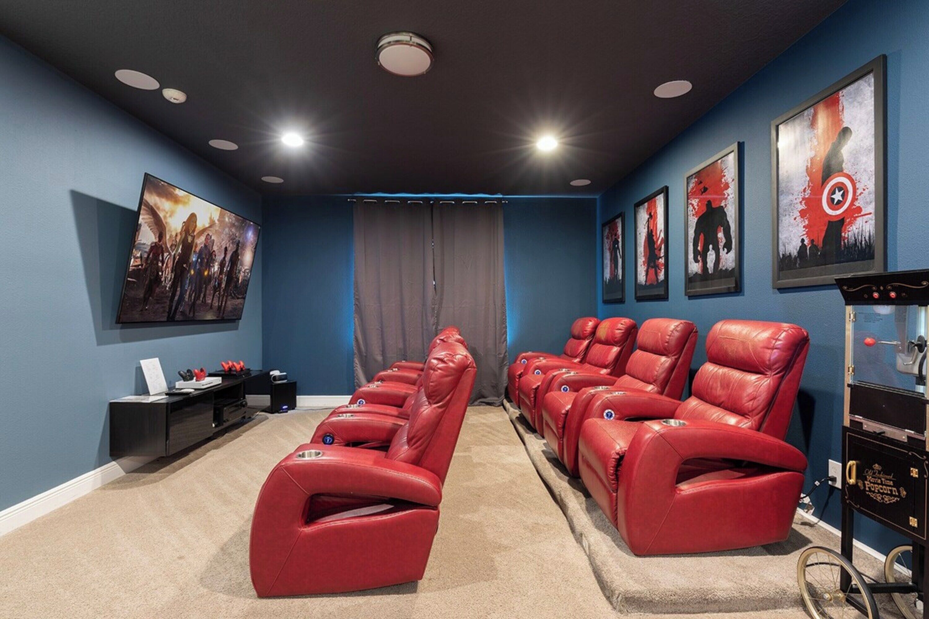 Ein Heimkino mit roten Liegesesseln, einer schwarzen Unterhaltungsanlage und gerahmten Postern an den Wänden.