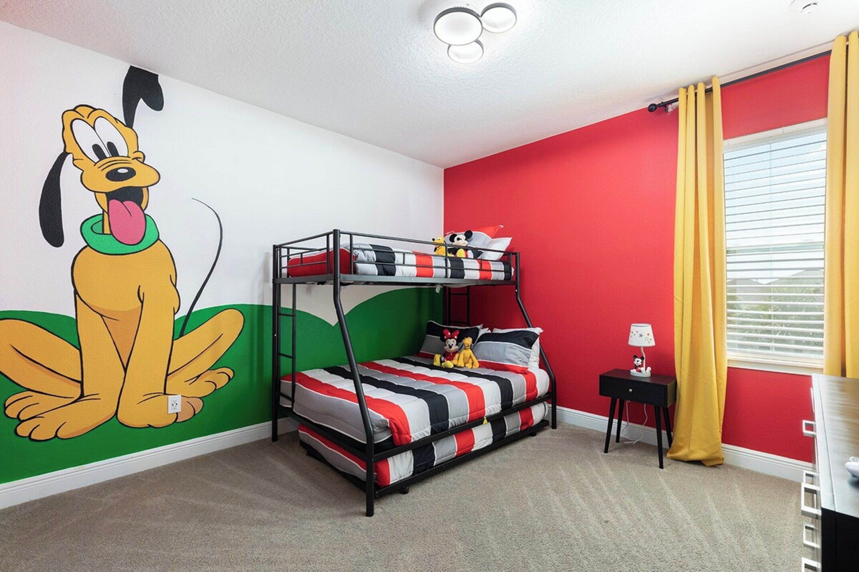 A bunk bed room with a cartoon dog mural, a red wall, and a yellow curtain.