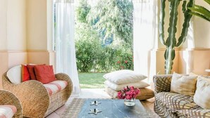 Un salon avec des meubles en osier, un cactus et une vue sur un jardin.