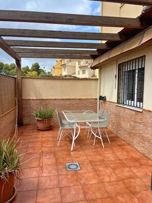 Relax on the covered patio surrounded by lush greenery and enjoy meals at the table and chairs.