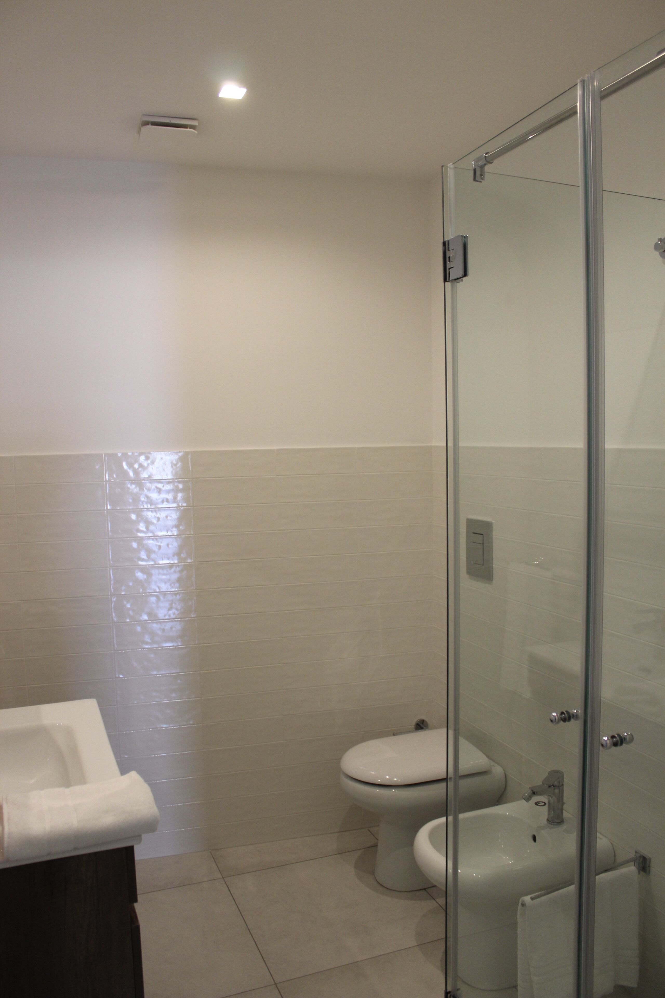 Un bagno con cabina doccia in vetro, un water e un lavandino.