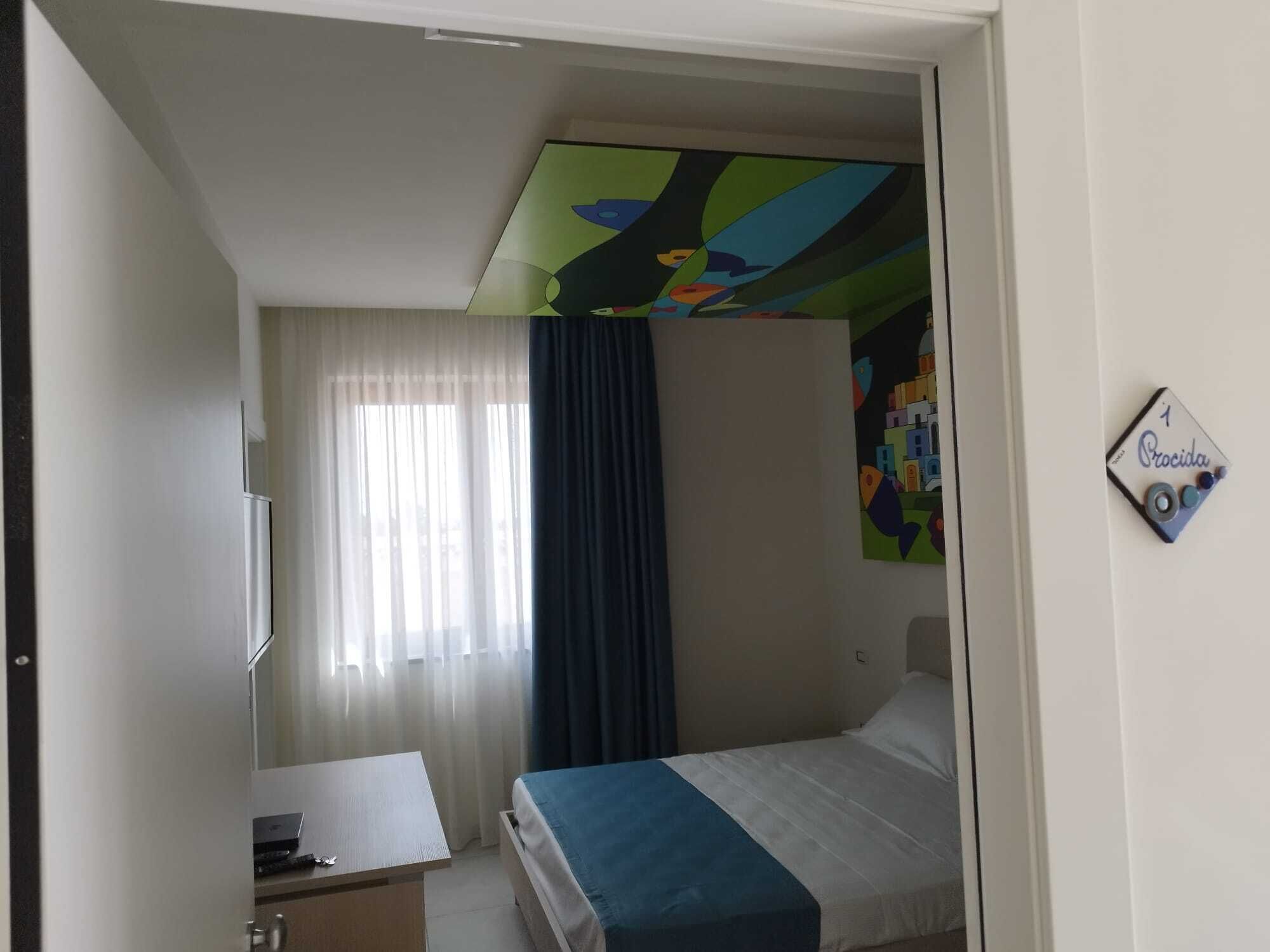Un dormitorio con cama, escritorio y ventana con cortinas.