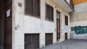 Un edificio con puertas numeradas, ventanas protegidas con barrotes y una pared cubierta de grafitis.