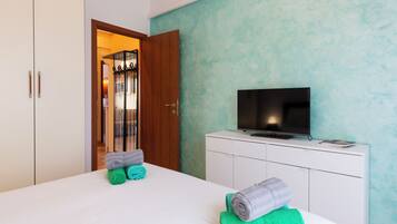 A hotel room with a bed, a television, a wardrobe, and a door leading to a bathroom.