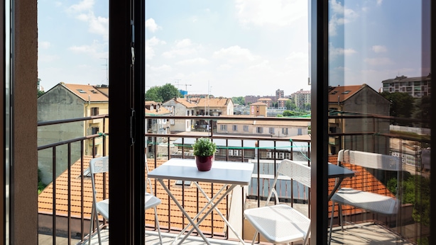 Un balcón con mesa y sillas, una planta en maceta y vista panorámica de la ciudad.