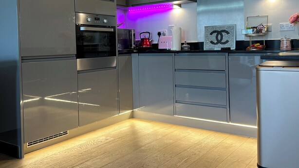 A modern kitchen with sleek cabinetry, a built-in oven, and a purple under-cabinet lighting. - Stunning 1-bed Apartment in Dartford (Dartford)