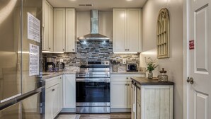 Una cocina moderna con electrodomésticos de acero inoxidable, armarios de tonos claros y salpicadero de piedra.