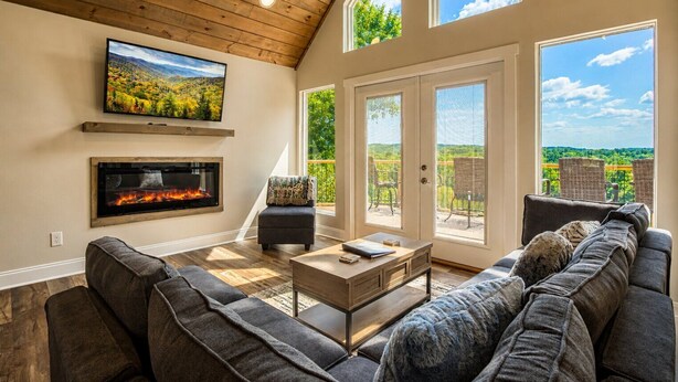 Una sala de estar con chimenea, televisor grande y sofá.