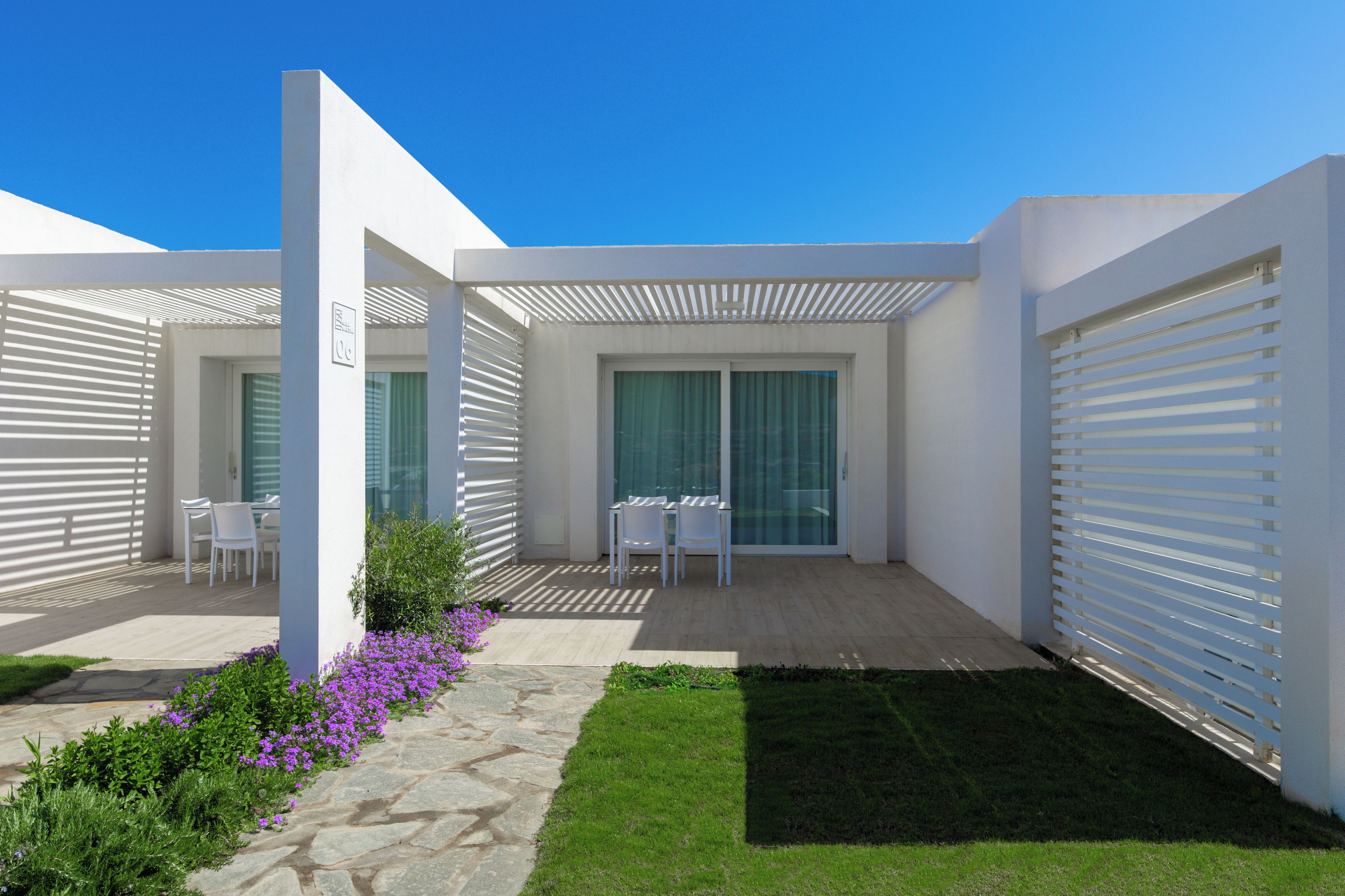 A modern outdoor patio area with a seating arrangement, a glass door entrance, and a stone pathway.