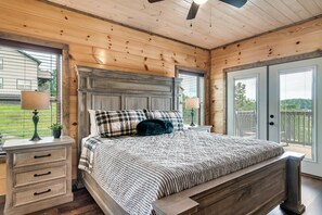 Relax in this serene bedroom with a large bed, nightstand, and window offering a view of the surrounding landscape.