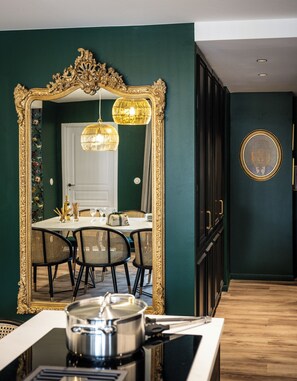En matplats med en stor, utsmyckad spegel, en kristallkrona och ett bord dukat för fyra personer.