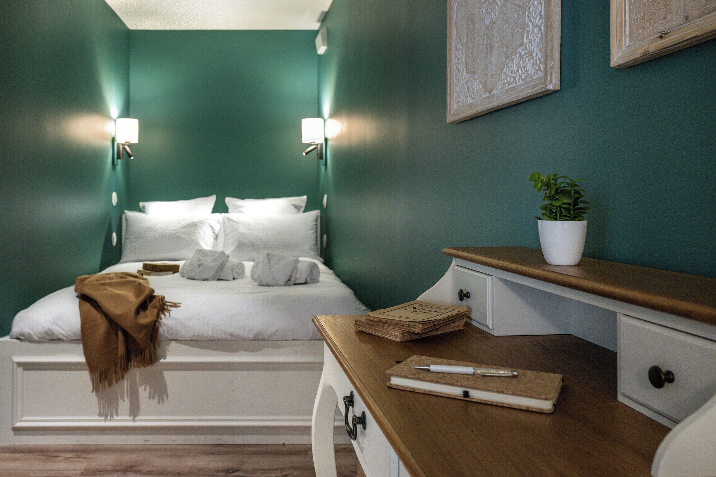 A neatly arranged bedroom with a bed, bedside tables, and a potted plant.