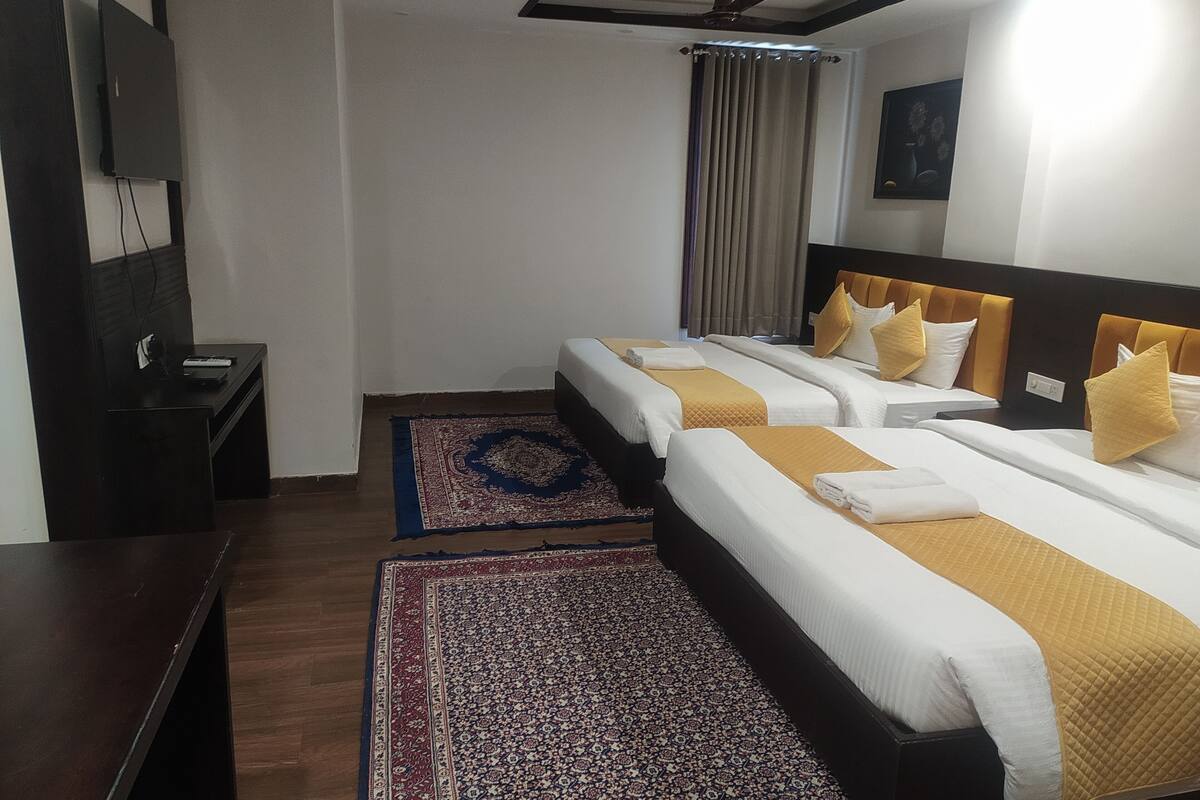 Een hotelkamer met twee bedden, een bureau, een televisie en een raam met gordijnen.