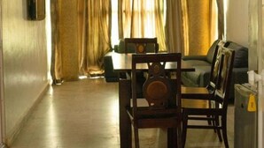 A living room with a dining table and chairs, a sofa, and a TV mounted on the wall. - Biggie Hotel and Suites  (Lagos)
