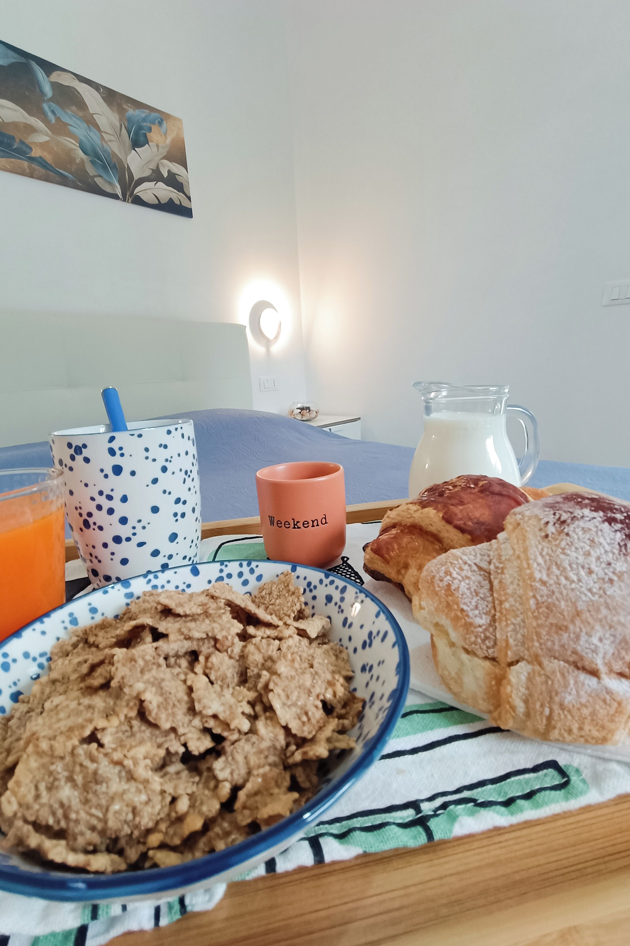 Una tavola per la colazione con una ciotola di cereali, un boccale di latte, dolci e una tazza.