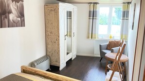 A room with a white cabinet, a chair, a window with curtains, and a radiator. - Cosy cottage in peaceful rural retreat (Chalais)