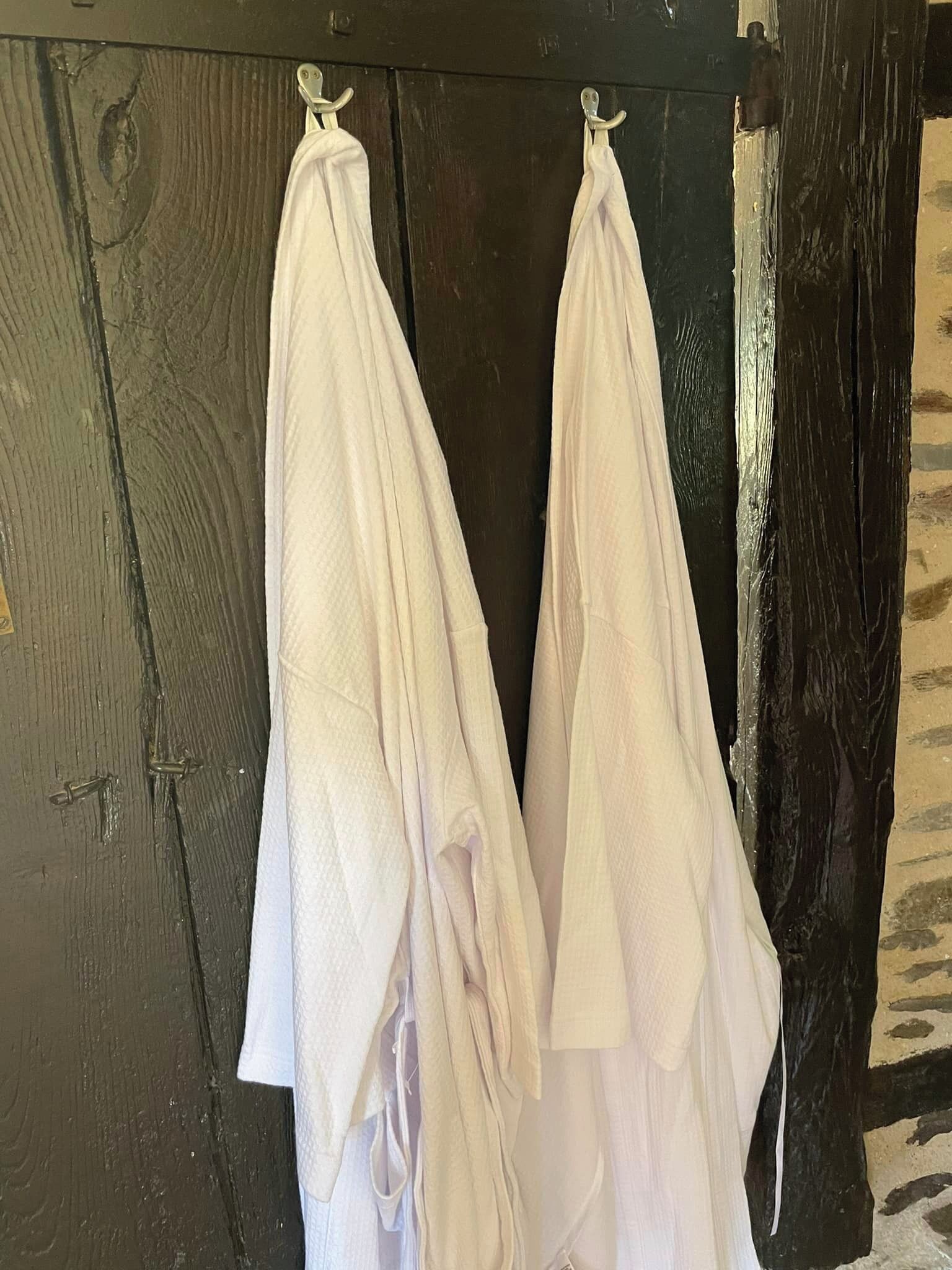 Two white towels hanging on a wooden door.