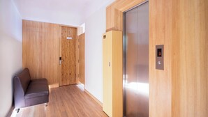 A modern room with a wooden floor, a sofa, and a wooden wardrobe with a door. - Grandma Lu's Saigon Japan Town (Ho Chi Minh City)