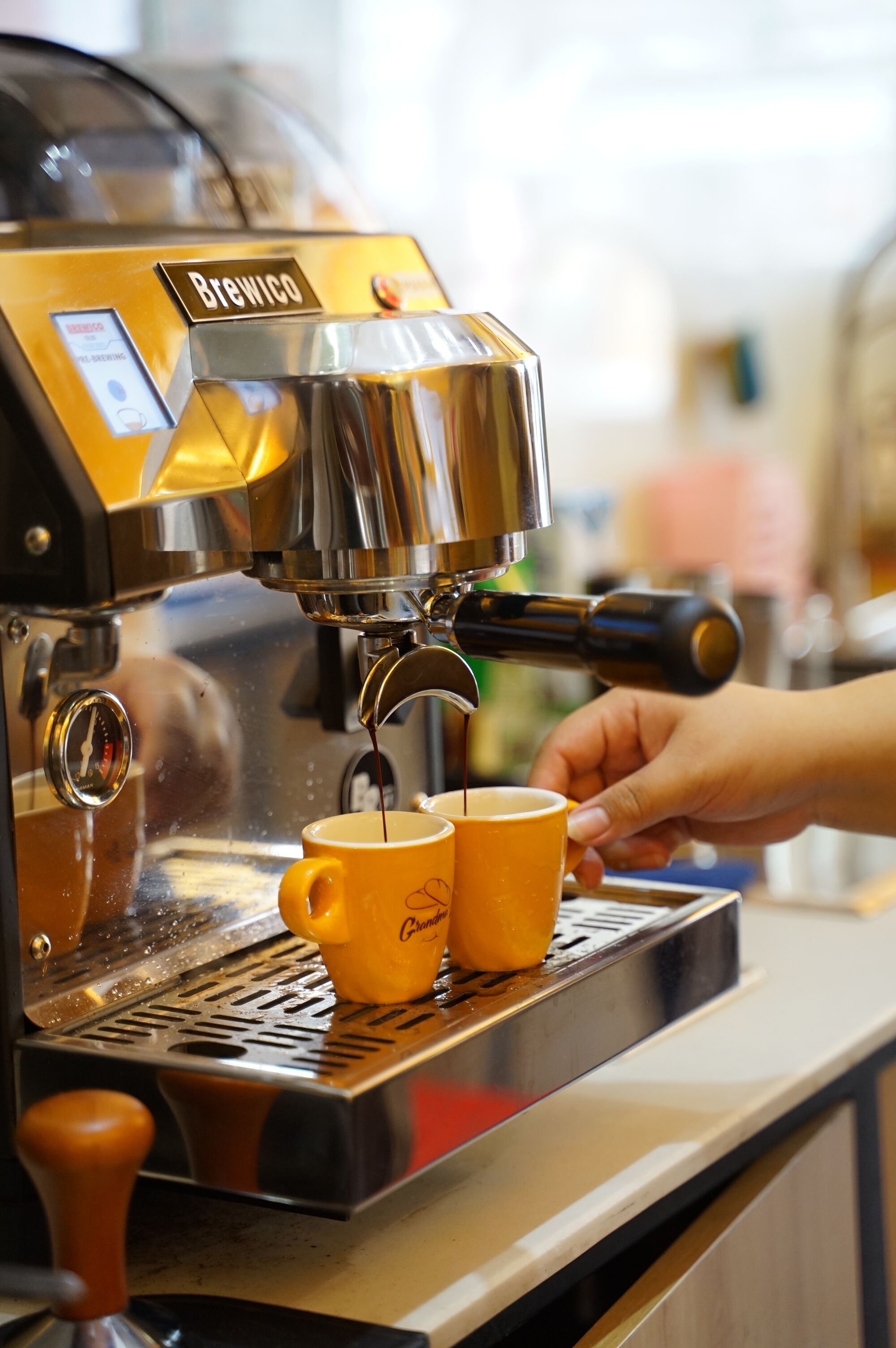 A coffee machine dispensing coffee into two yellow cups.