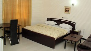 Una camera d'albergo con un letto, una scrivania, una sedia e un comodino.