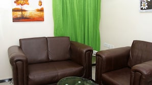 Una stanza con due divani in pelle marrone, una tenda verde e un quadro appeso al muro.
