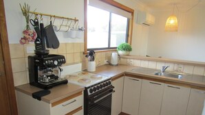 Una cocina compacta con estufa, horno, fregadero y cafetera.