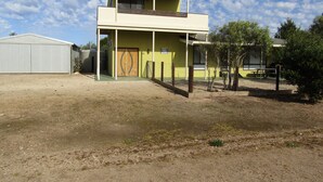 Un edificio de dos pisos con techo plano, un balcón en el nivel superior y una puerta con diseño decorativo.
