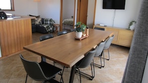 Una cocina moderna con una mesa de comedor de madera, sillas, una pequeña isla y un televisor montado en la pared.