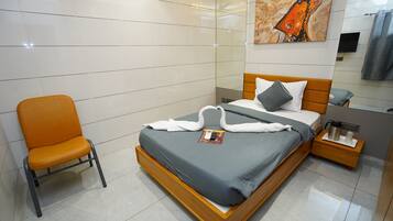 Una habitación de hotel moderna con una cama grande, una mesita de noche de madera, una silla y un cuadro en la pared.
