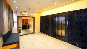 Ein Hotel-Empfangsbereich mit einer Rezeption, einem Schild mit der Aufschrift 'Hotel Sunshine' und einem Aufzug.