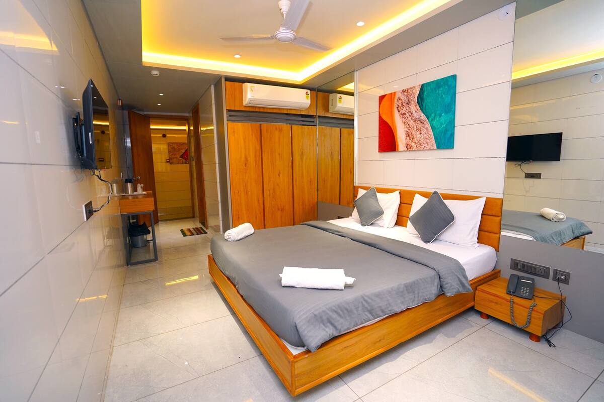 A modern hotel room with a large bed, bedside table, and a TV.