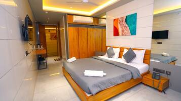 Una habitación de hotel moderna con una cama grande, una mesita de noche y televisión.