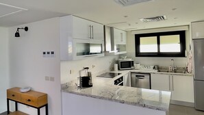 Una cocina moderna con armarios blancos, una isla central y electrodomésticos de acero inoxidable.