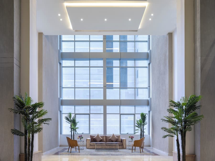 A spacious lobby with a large window, a sofa, and two potted plants.