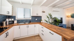 Een moderne keuken met witte kastjes, een houten aanrechtblad en een blauwe betegelde achterwand.