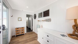 Een moderne kamer met een witte dressoir, een houten kastje en een spiegel aan de muur.