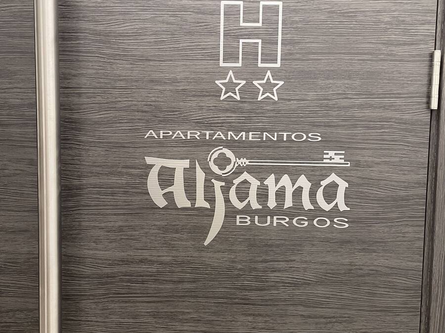 Puerta metálica con un logo y texto que indica que pertenece al hotel 'Aljama Burgos'.